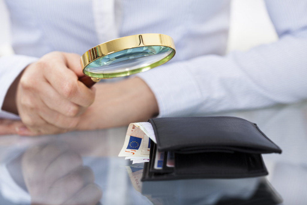 Businessperson With Magnifier And Wallet