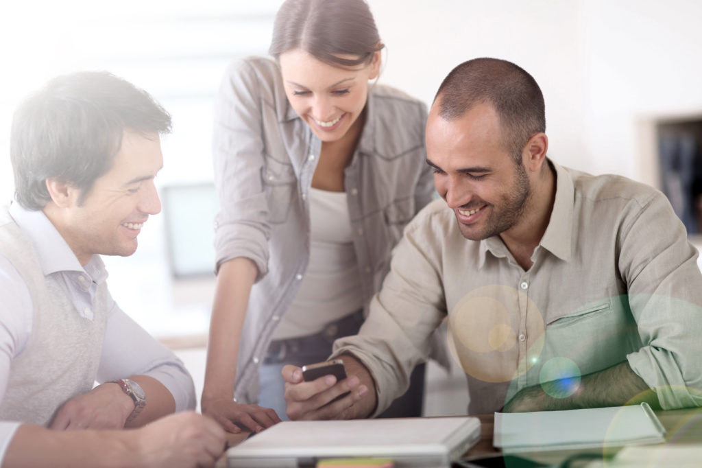 People in office laughing at reading text on smartphone